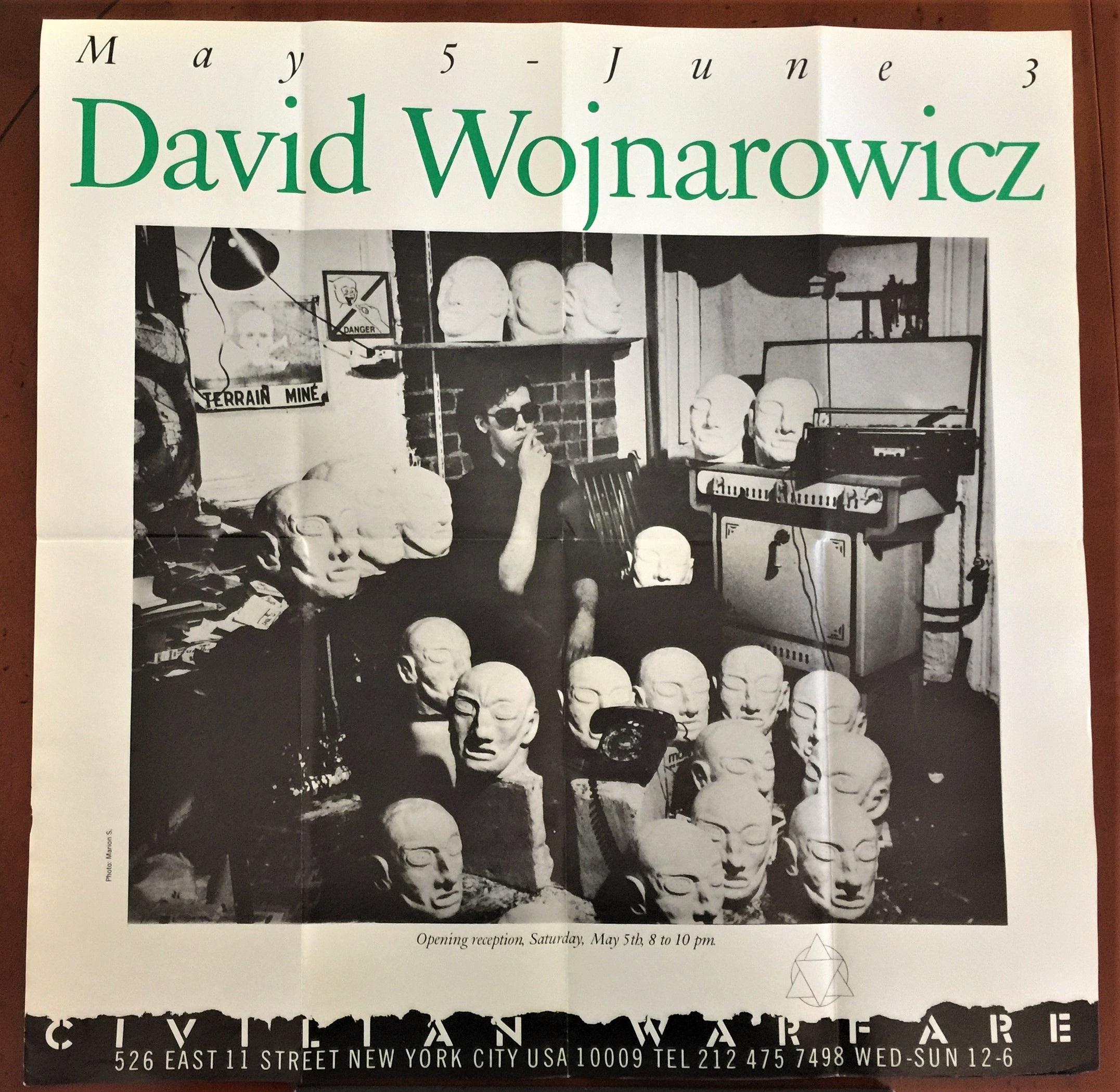 Civilian Warfare poster for David Wojnarowicz solo show May 5 - June 3, 1984. Photo of David surrounded by his Metamorphosis series in his Bowery studio by Marion Scemama.